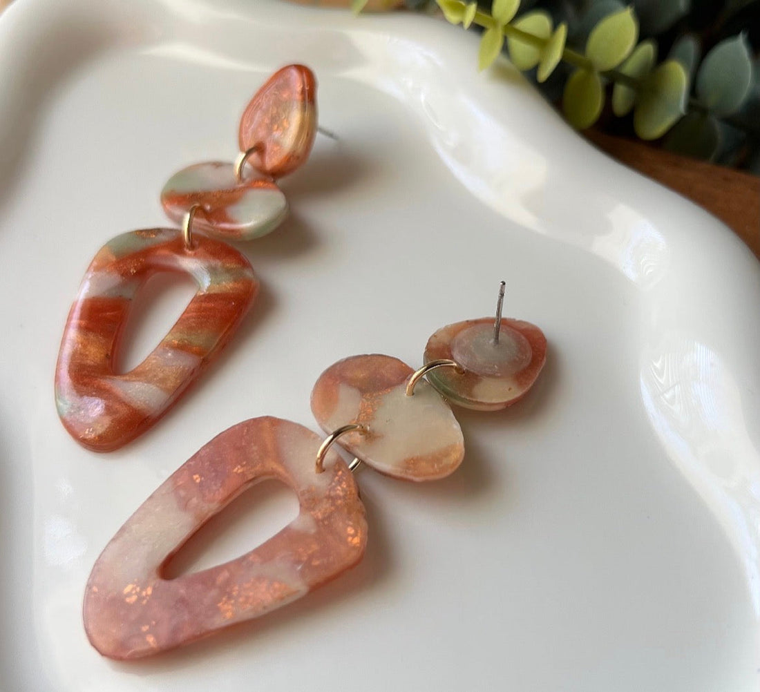 Front and back of marbled polymer clay earrings showing the front of the earring, and the back with the translucent clay backing 