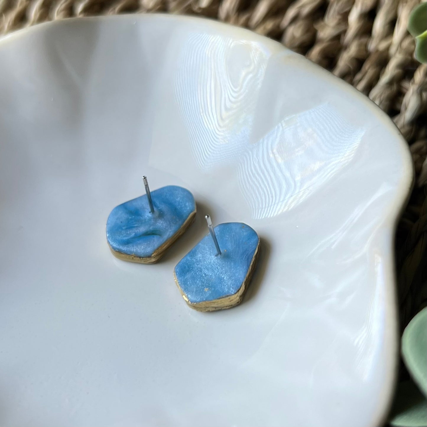 The Marina polymer clay statement stud earrings in ocean blue with gold edges, lightweight and coastal-inspired. Photo shows back of earrings that have stainless steel posts embedded with clay for durability.