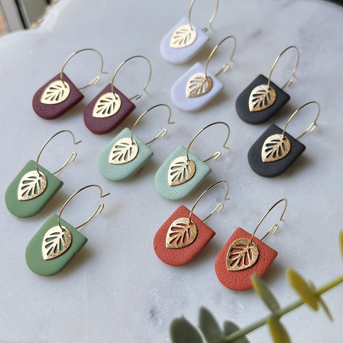 Arch-shaped polymer clay dangle earrings with gold leaf accents in multiple colors