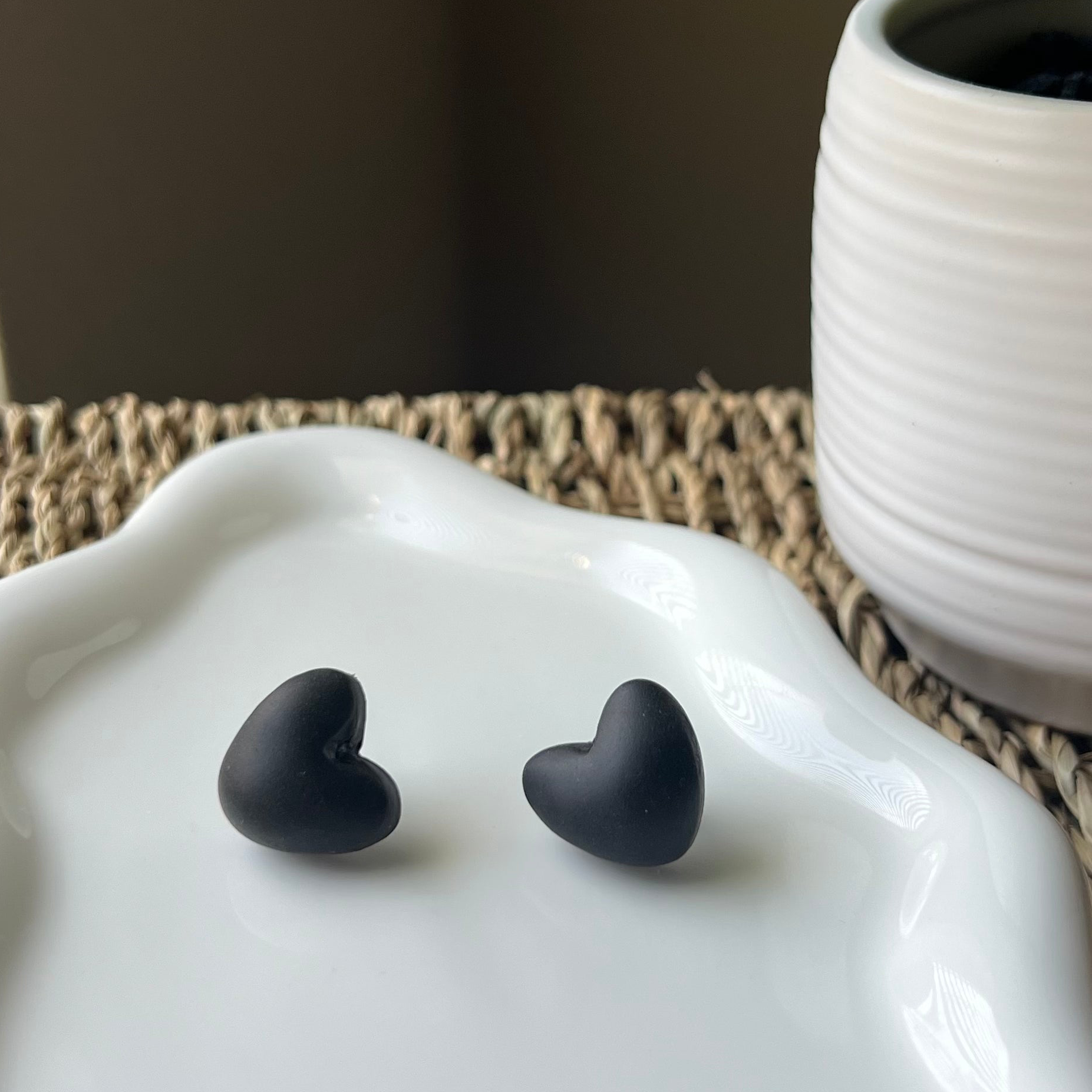 black puffy heart clay earrings sitting on white plate 