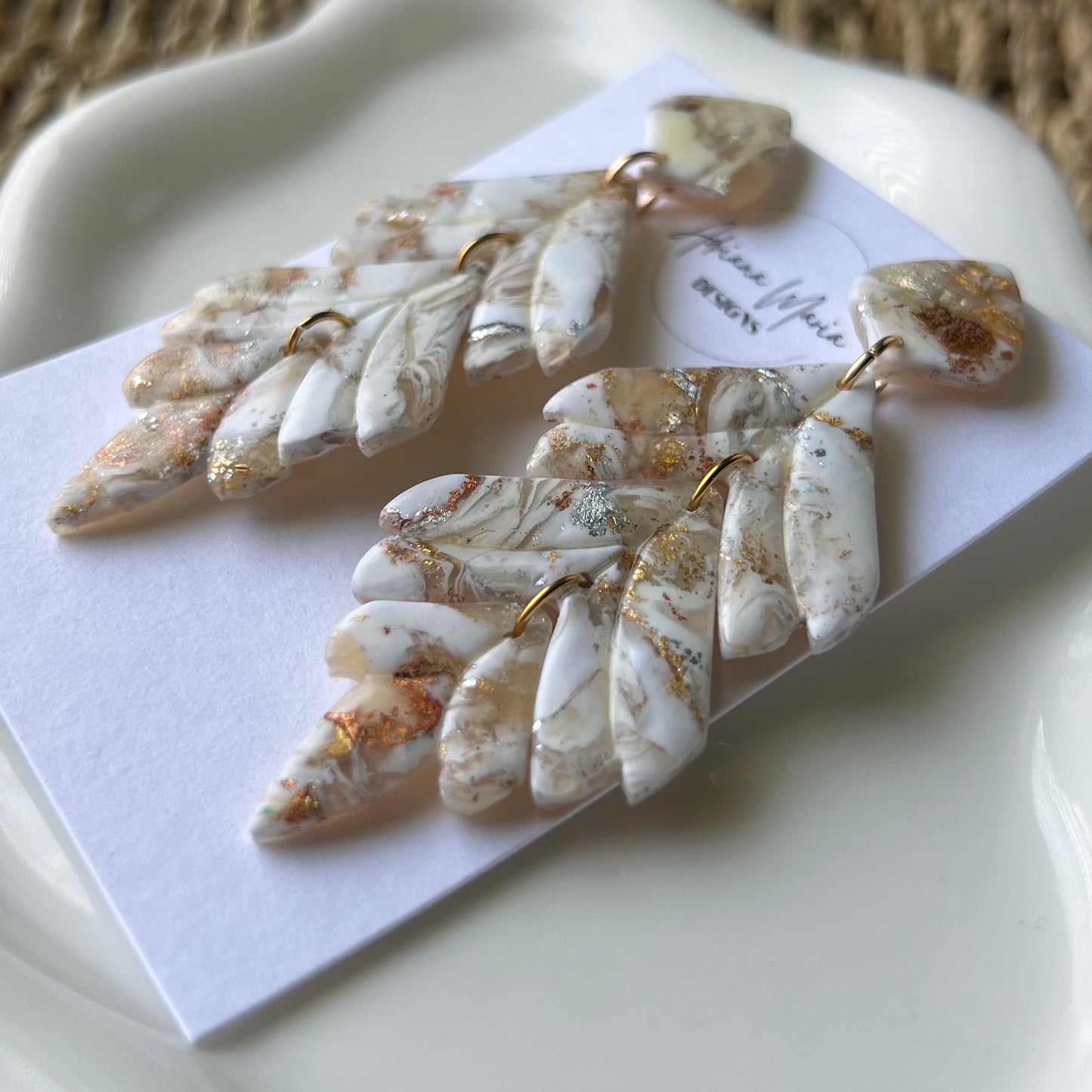 Pair of leaf-shaped earrings with gold & silver accents on a white card.
