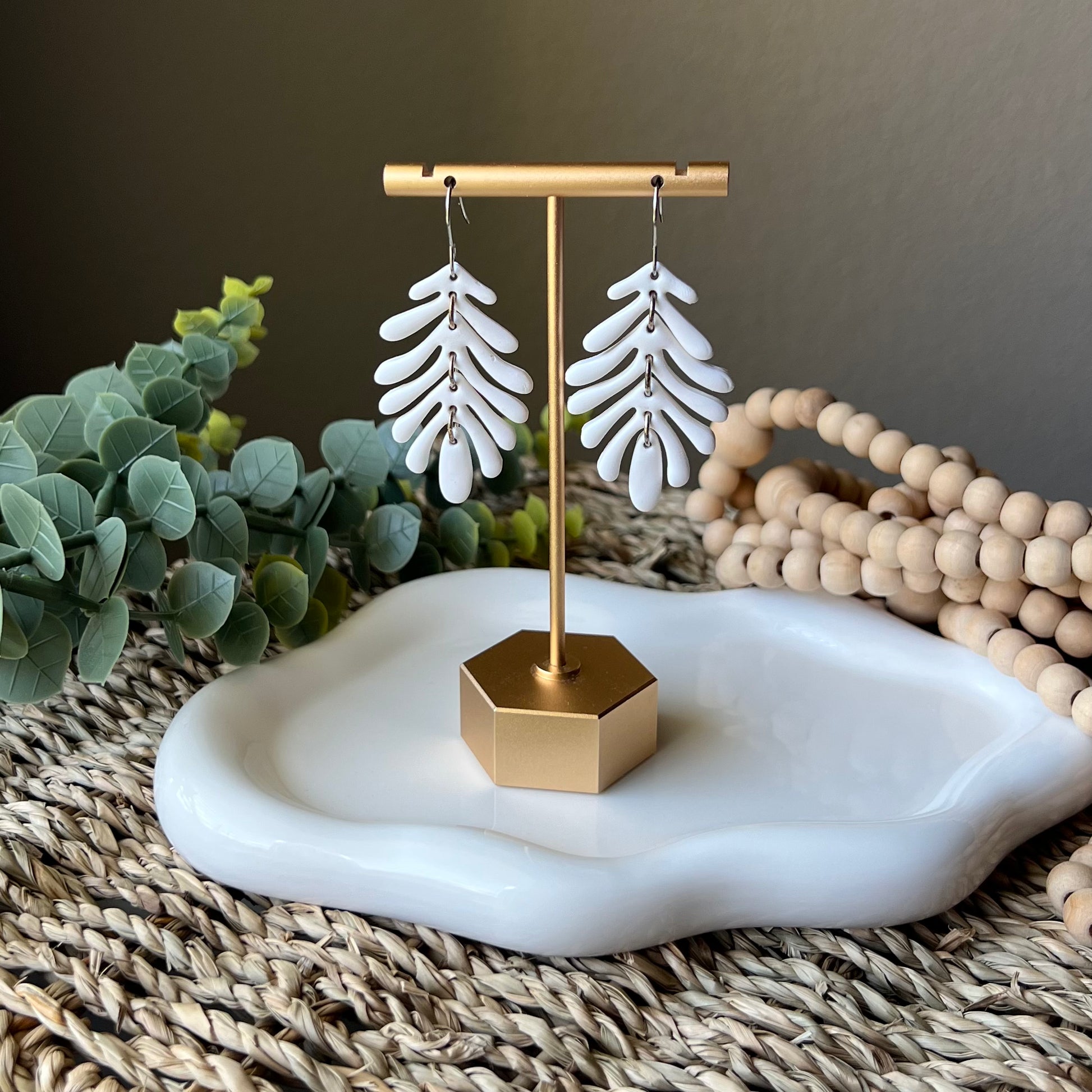 white clay earrings hanging from earring stand 