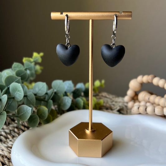 black heart earrings hanging from earring display stand