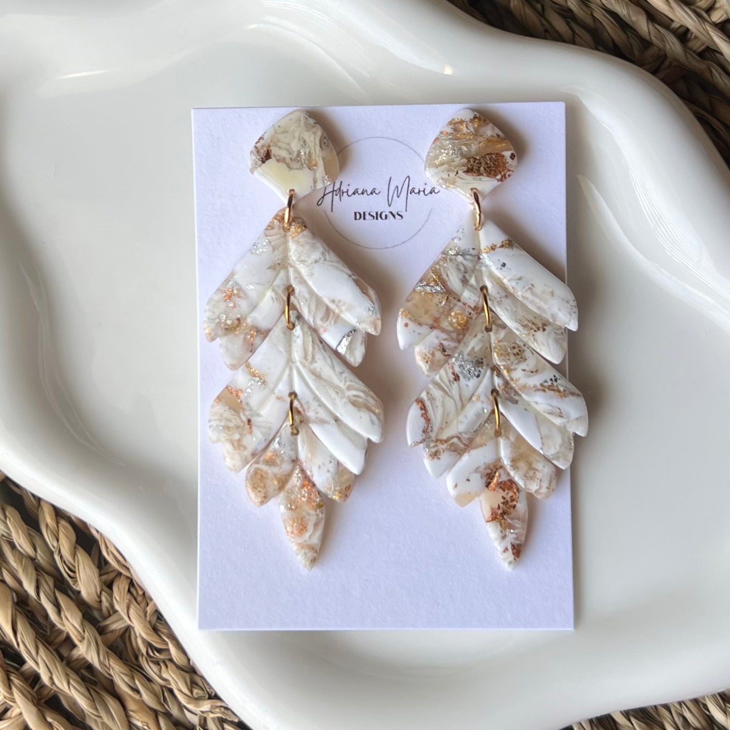 Marbleized leaf-shaped earrings on a branded card with a woven mat background